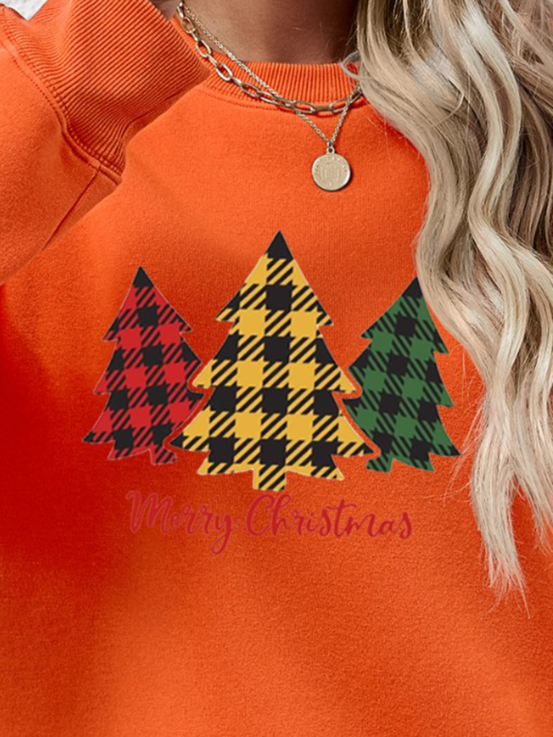 Orange crewneck sweatshirt with plaid trees graphic and Merry Christmas text.