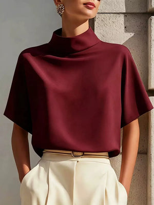 Burgundy mock neck t-shirt with relaxed sleeves in polyester, styled with cream trousers.