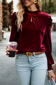 Burgundy velvet keyhole puff-sleeve blouse with mock neck and cinched cuffs.
