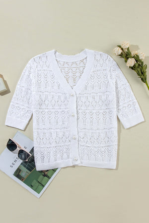 White openwork crochet cardigan with V-neck, pearl buttons, and 3/4 sleeves.