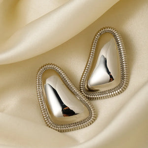 Sculpted silver vermeil earrings with textured edges on satin fabric