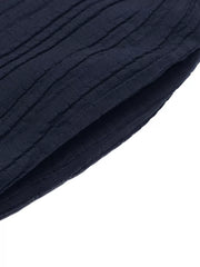 Navy blue textured fabric detail of a ruffled peplum tube top and wide-leg pants set.