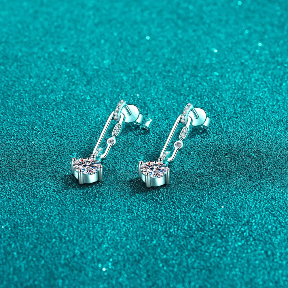Silver link moissanite drop earrings with dazzling stones on a textured teal background.