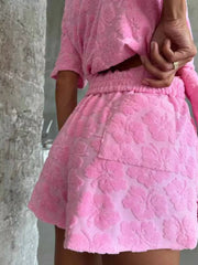 Pink textured floral button-up shirt and shorts set with elastic waist shorts and pocket detail.