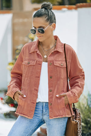 Distressed denim trucker jacket in salmon with frayed edges and button front.