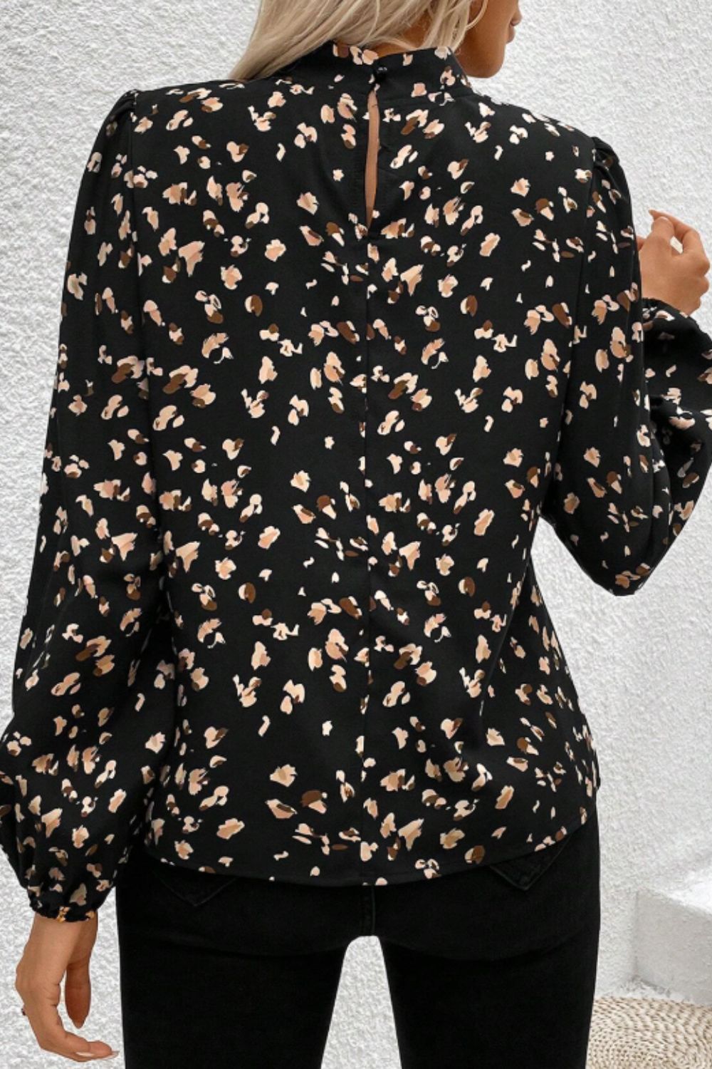 Black high-neck blouse with abstract print and long puff sleeves.