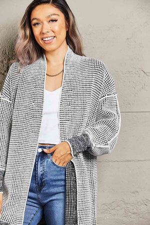 Textured open cardigan in black and white with puff sleeves and ribbed cuffs.