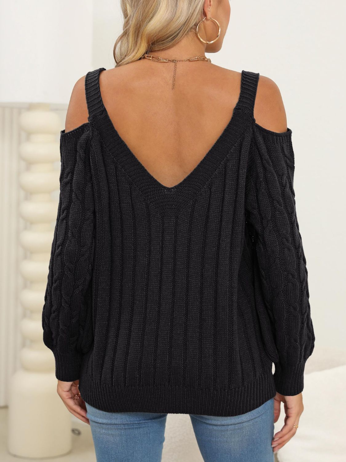 Black cable knit cold shoulder sweater with V-neck and balloon sleeves.