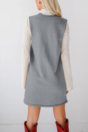 Sleeveless gray knit dress with V-neck and pockets, layered over a cream ribbed turtleneck.