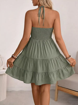Green smocked halter mini dress with tiered skirt and tie back detail.
