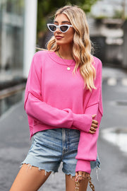 Pink ribbed knit batwing sweater with crew neck and dropped shoulders.