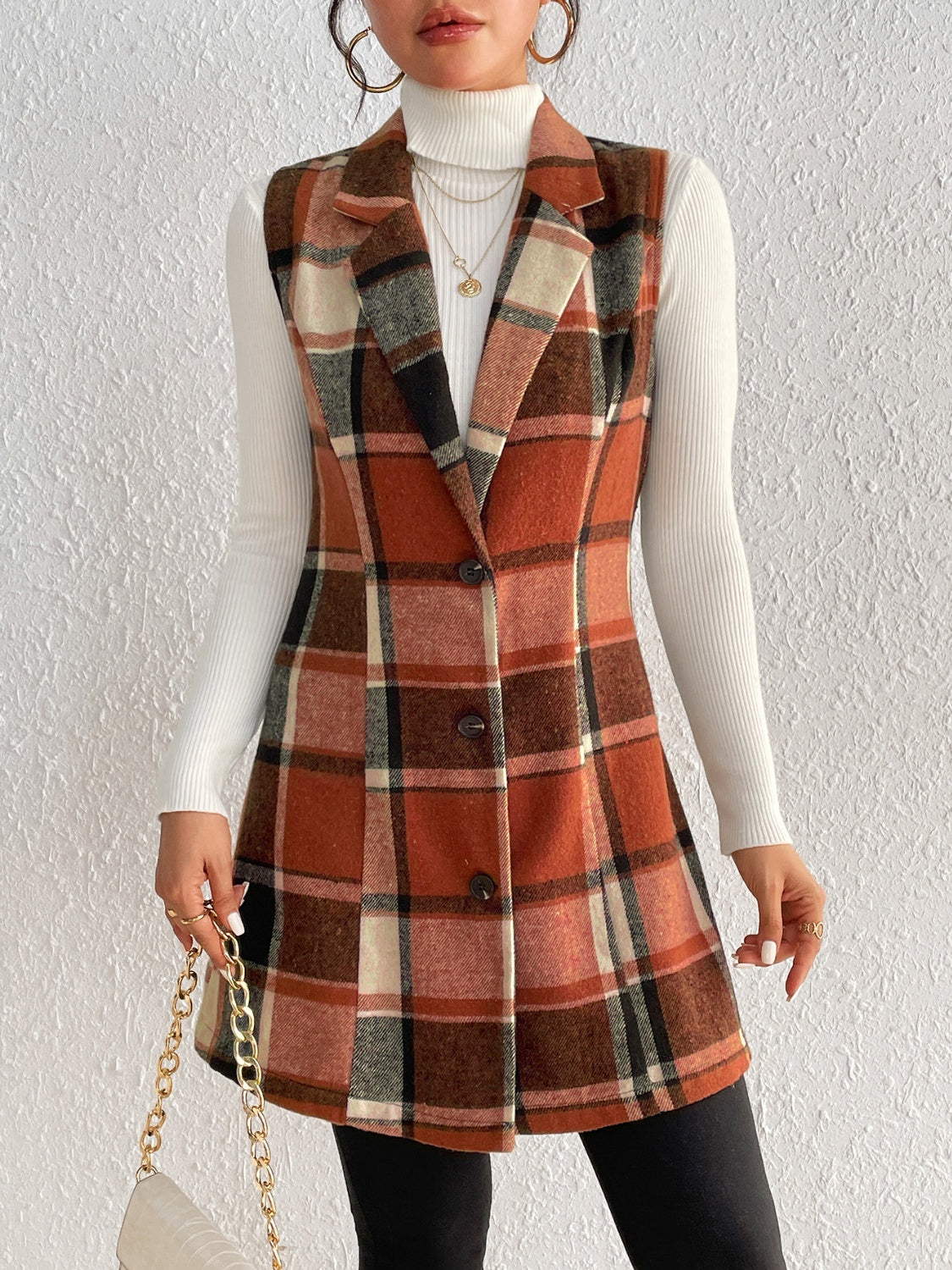 Tailored plaid sleeveless blazer dress in caramel tones, buttoned A-line cut, worn over a white turtleneck.
