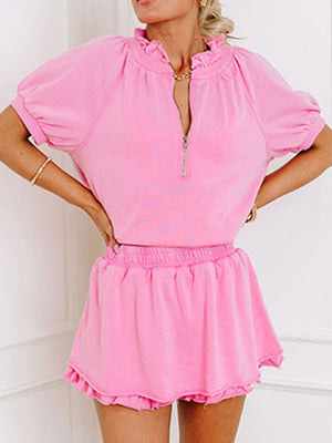 Pink cotton co-ord set with ruffled neckline, zip-up top, and ruffled hem shorts.