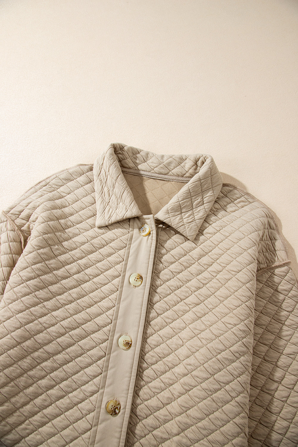 Beige diamond quilted oversized button-up jacket with a collared neckline and button closure.
