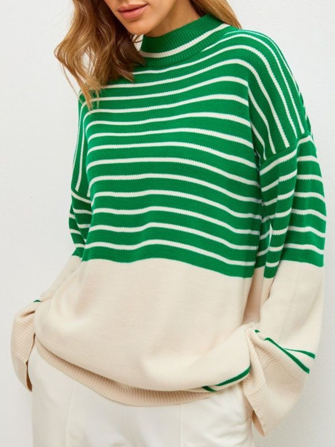 Green and white striped knit sweater with bell sleeves and a colorblock cream bottom.