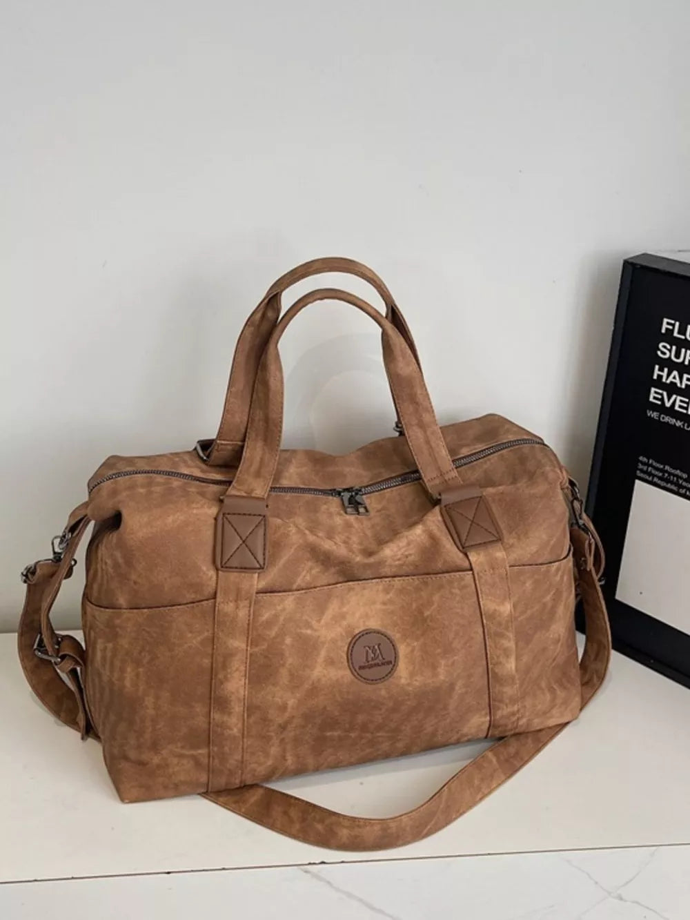 Distressed brown leather travel duffel bag with adjustable strap and exterior pockets.