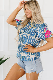 Abstract print puff sleeve top in beige with blue graphics and embroidered floral detail on sleeves.