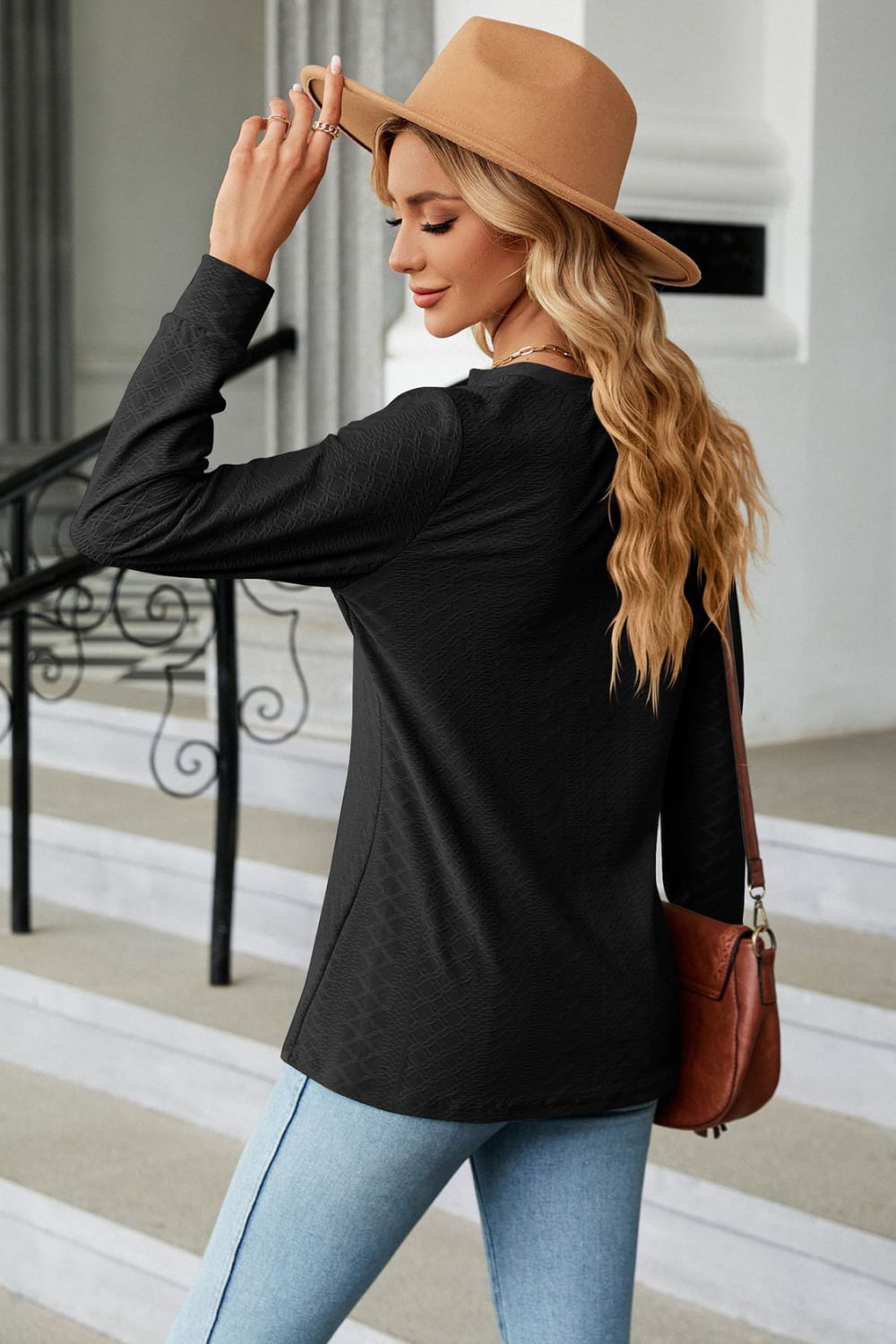 Black textured henley blouse with button detail and long sleeves.