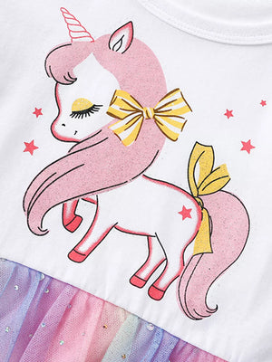 White baby dress with unicorn print, yellow bow, and rainbow glitter tulle skirt.