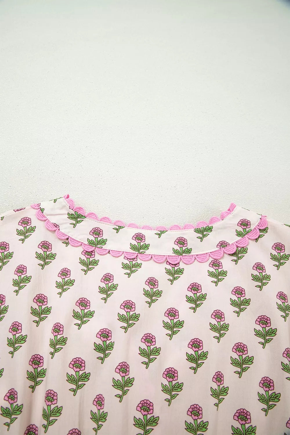 Floral v-neck midi dress in blush pink with scalloped trim and button front detail.