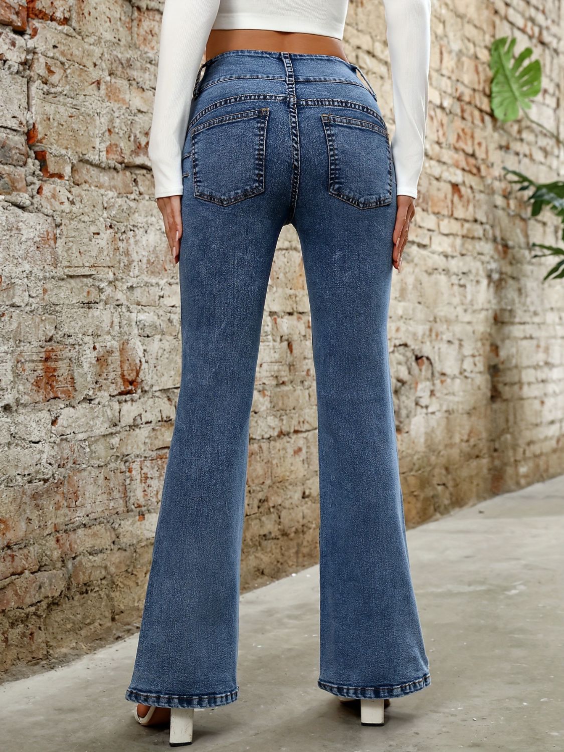 Medium wash cotton bootcut jeans with a sculpted waist and five-pocket styling.