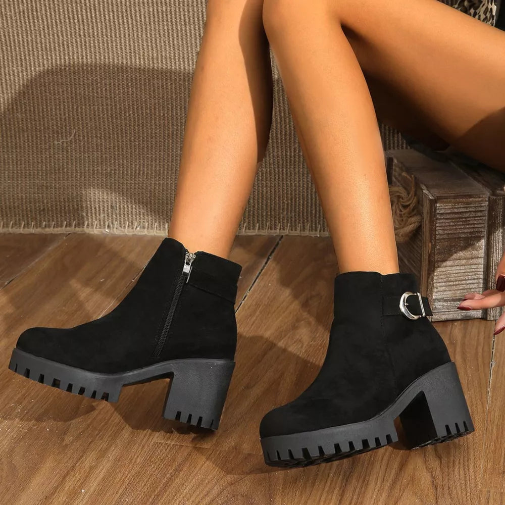 Black suede ankle boots with round toe, block heel, side zipper, and decorative buckle detail.