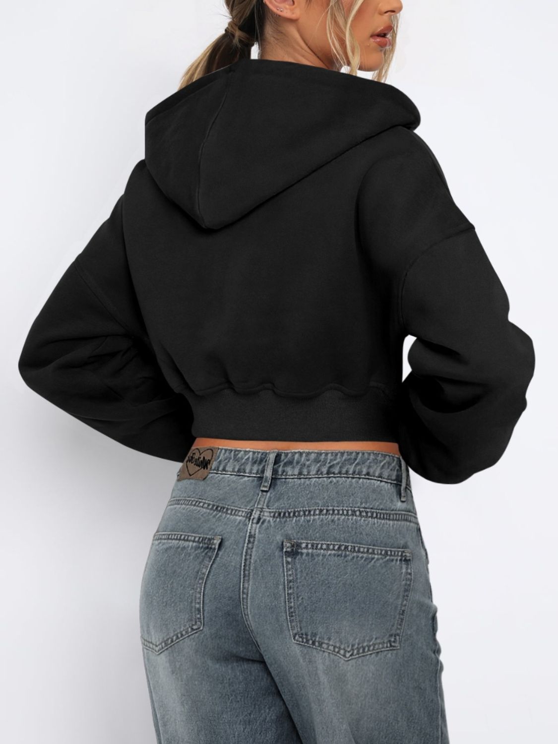 Black cropped zip-up hoodie with ribbed hem and full sleeves, shown from the back.