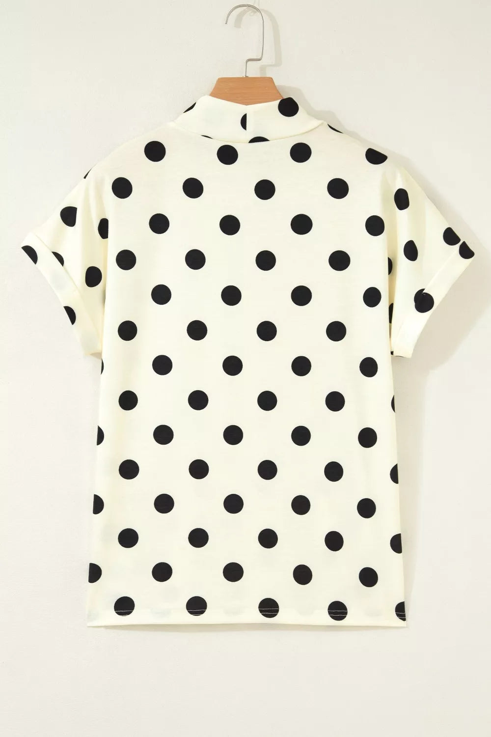 Cream polyester t-shirt with black polka dots, high neck, and short rolled sleeves.