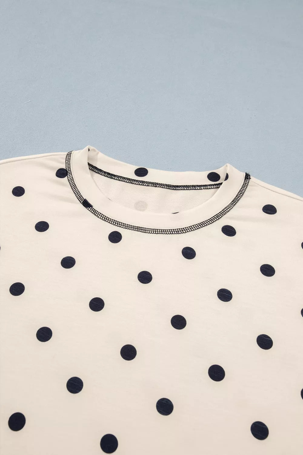 White polyester bikini top with navy polka dots and contrast stitching.