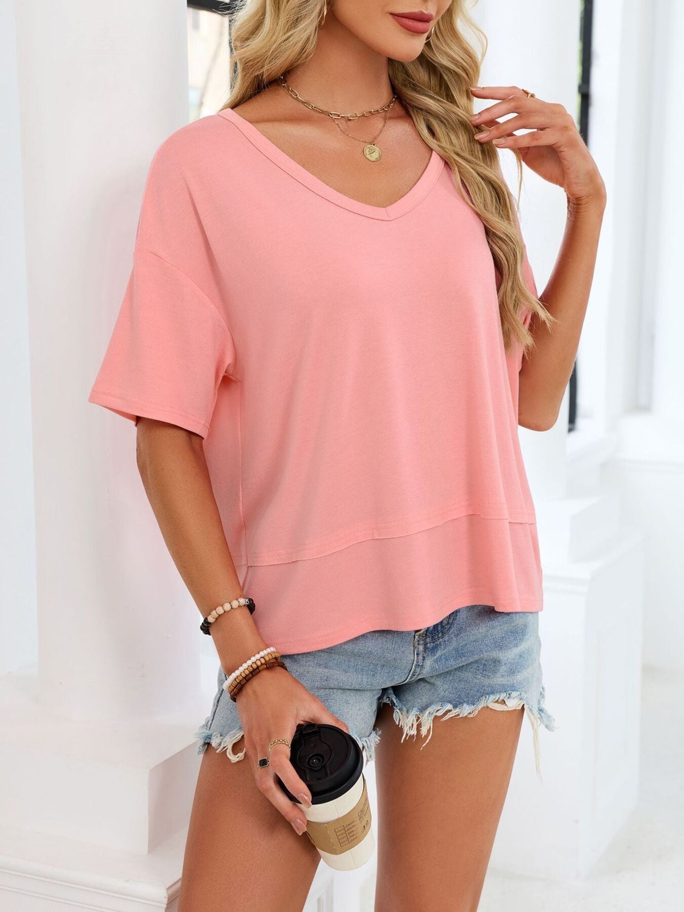 Relaxed fit pink v-neck t-shirt with short sleeves and a layered hem detail.