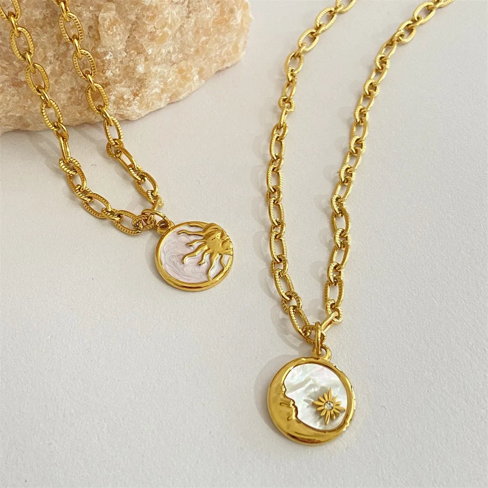 Gold chain necklaces with sun and moon medallions, one with a sunburst, the other with a crescent moon and star.
