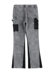 Dark gray bootcut jeans with black panels, paint splatters, and split hem