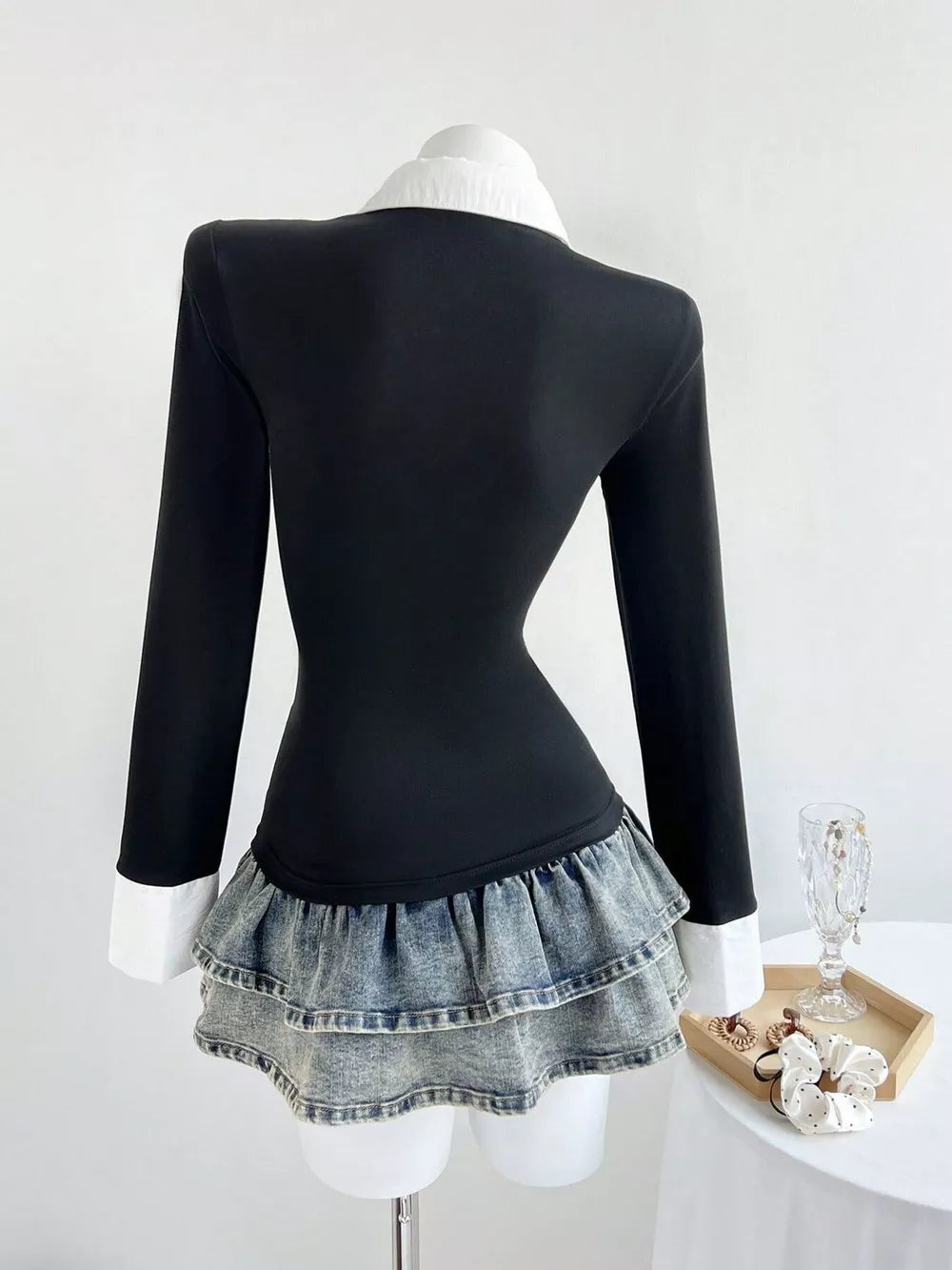 Black polo collar shirt with long sleeves and a tiered denim ruffle hem.