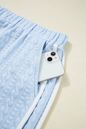 Light blue cable knit lounge shorts with white trim and a phone in the pocket.