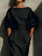Black midi dress with puff sleeves, boat neck, belted waist, and pockets.