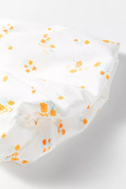 Maternity t-shirt in white cotton blend with orange and blue floral print, textured fabric detail.