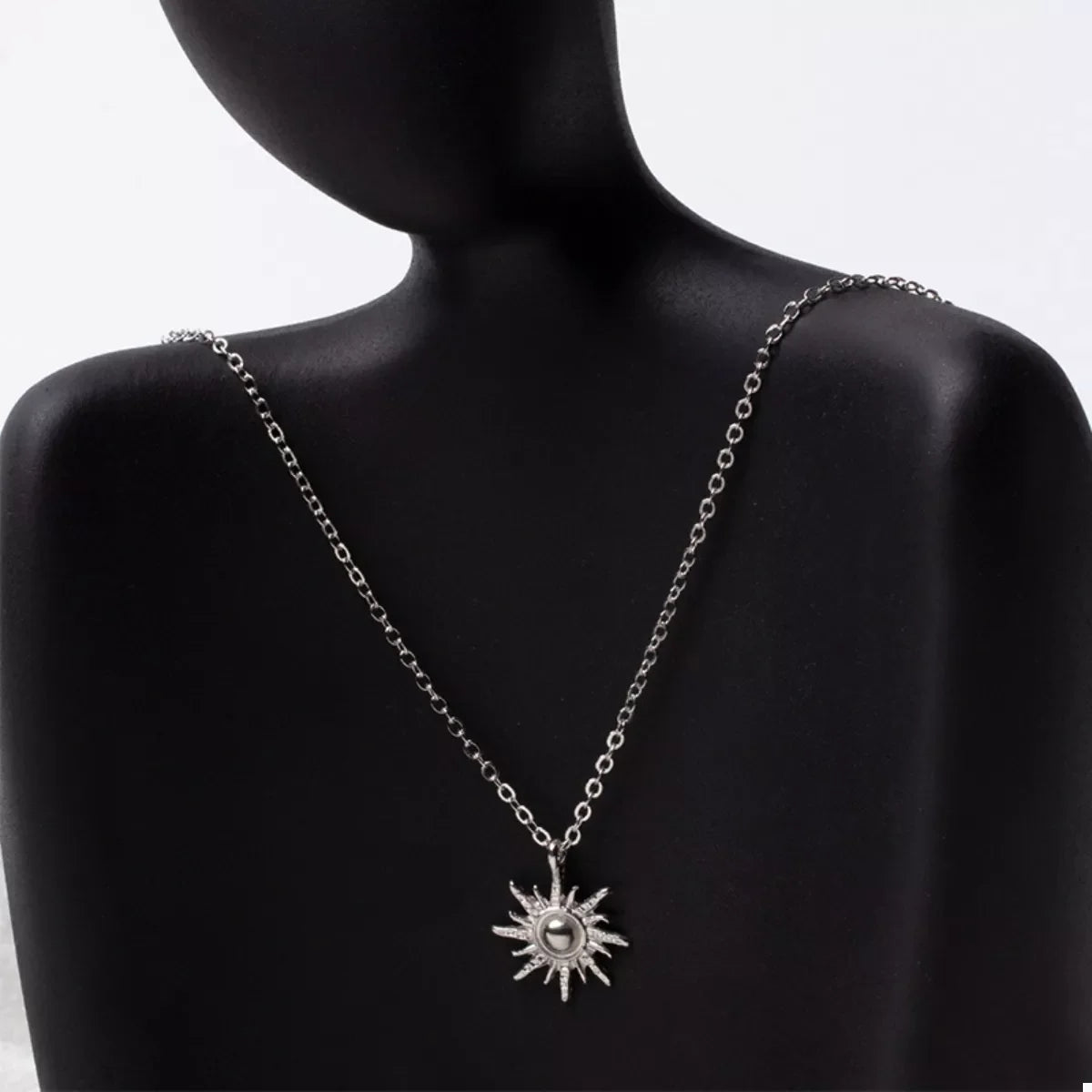 Silver sunburst pendant necklace with delicate chain and lace trim detail.