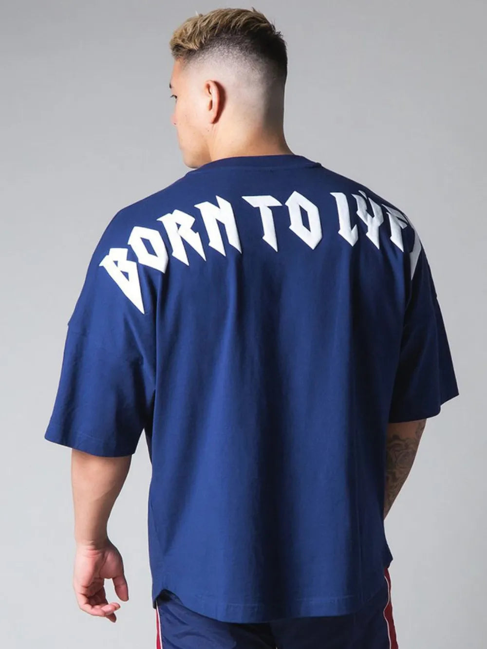 Royal blue oversized graphic tee with white "BORN TO LIVE" text on back.