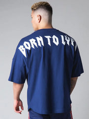 Royal blue oversized graphic tee with white "BORN TO LIVE" text on back.