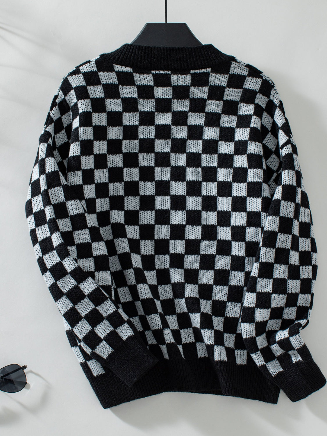 Checkerboard knit pullover sweater in black and white with a V-neck.