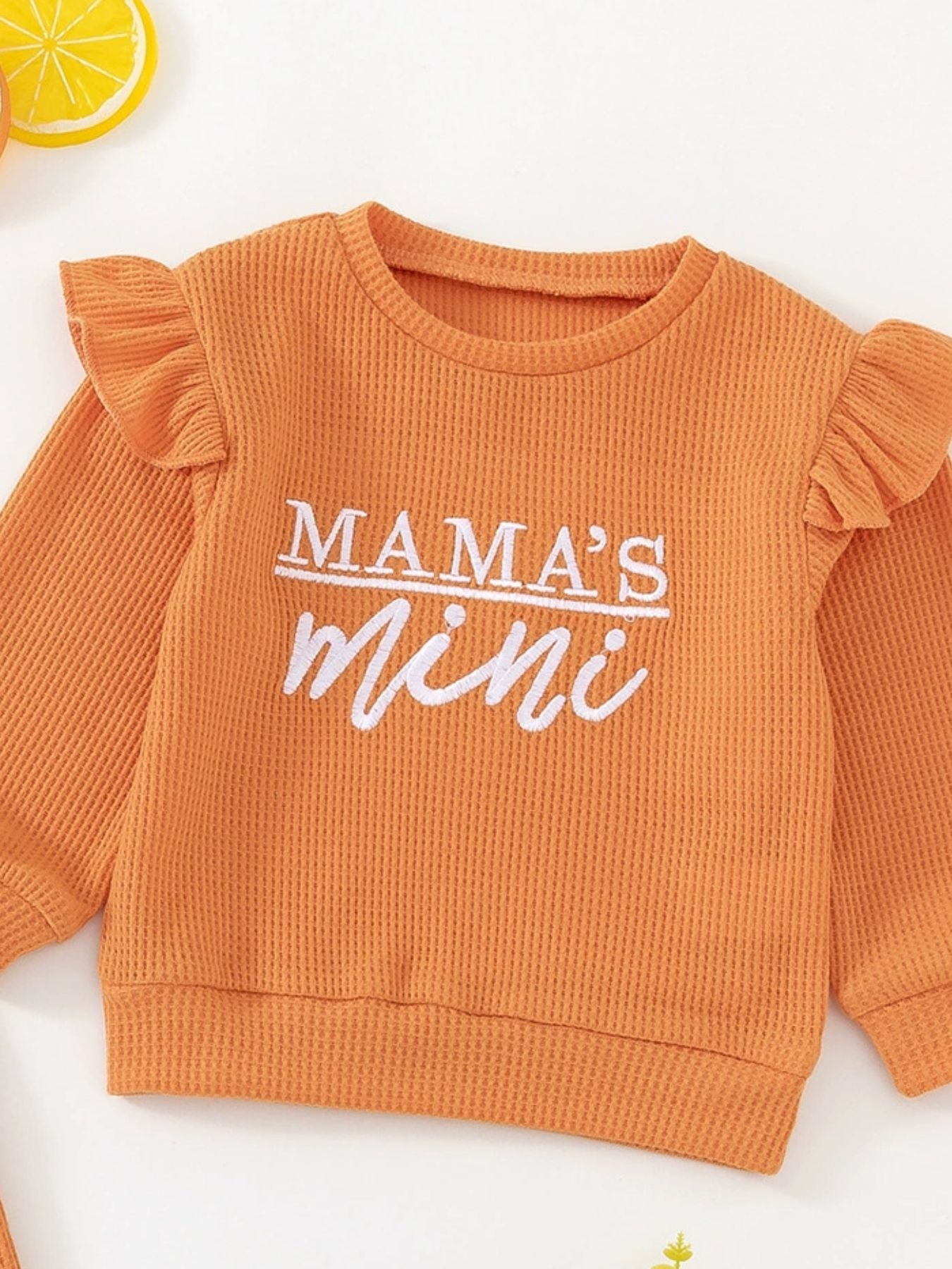 Orange waffle knit toddler top with ruffled sleeves and "Mama's mini" embroidery.