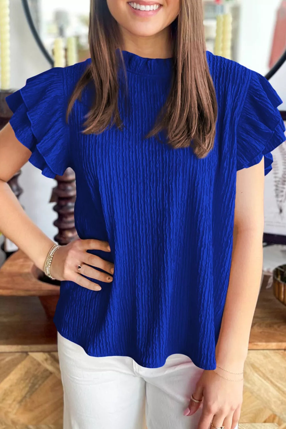 Blue textured short sleeve shirt with ruffle trim and mock neckline.