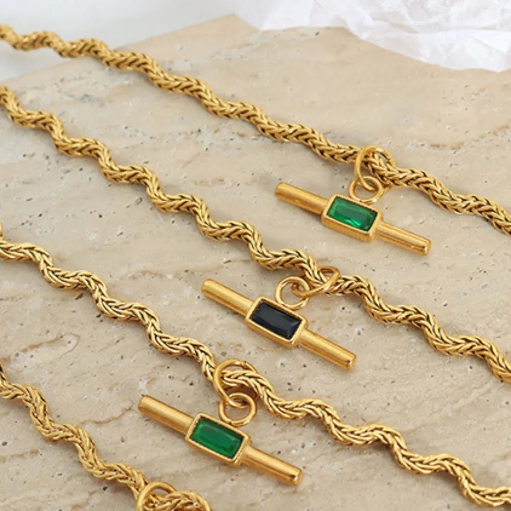 Gold rope chain necklaces with emerald bar pendants in dark green and black.