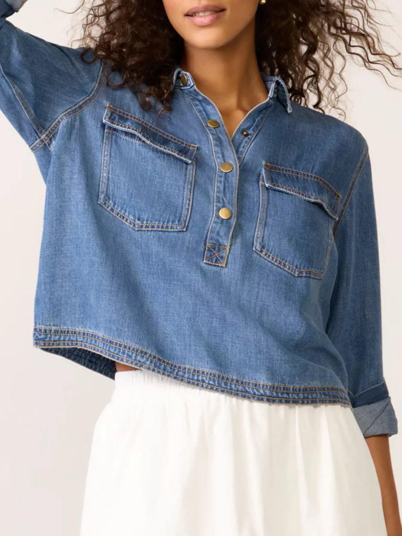 Blue denim cropped half snap shirt with two chest pockets and gold buttons.