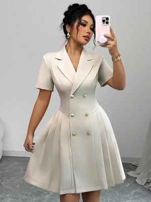 Beige double-breasted pleated blazer dress with gold buttons and short sleeves.