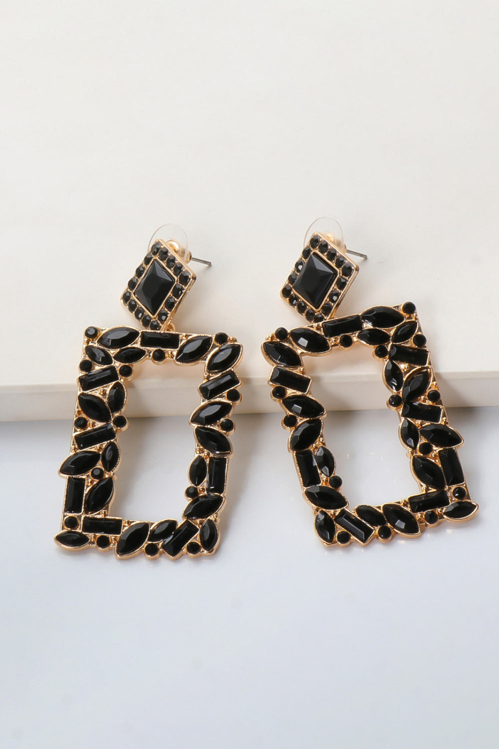 Black geometric jewel box earrings with gold alloy setting and faceted black stones.