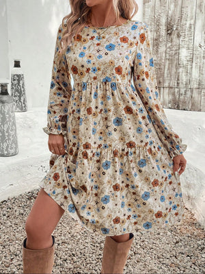 Charming floral tiered dress with long sleeves in beige with blue and brown flowers, ruffled cuffs.