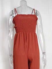 Orange-red smocked wide leg romper with spaghetti straps and pockets.