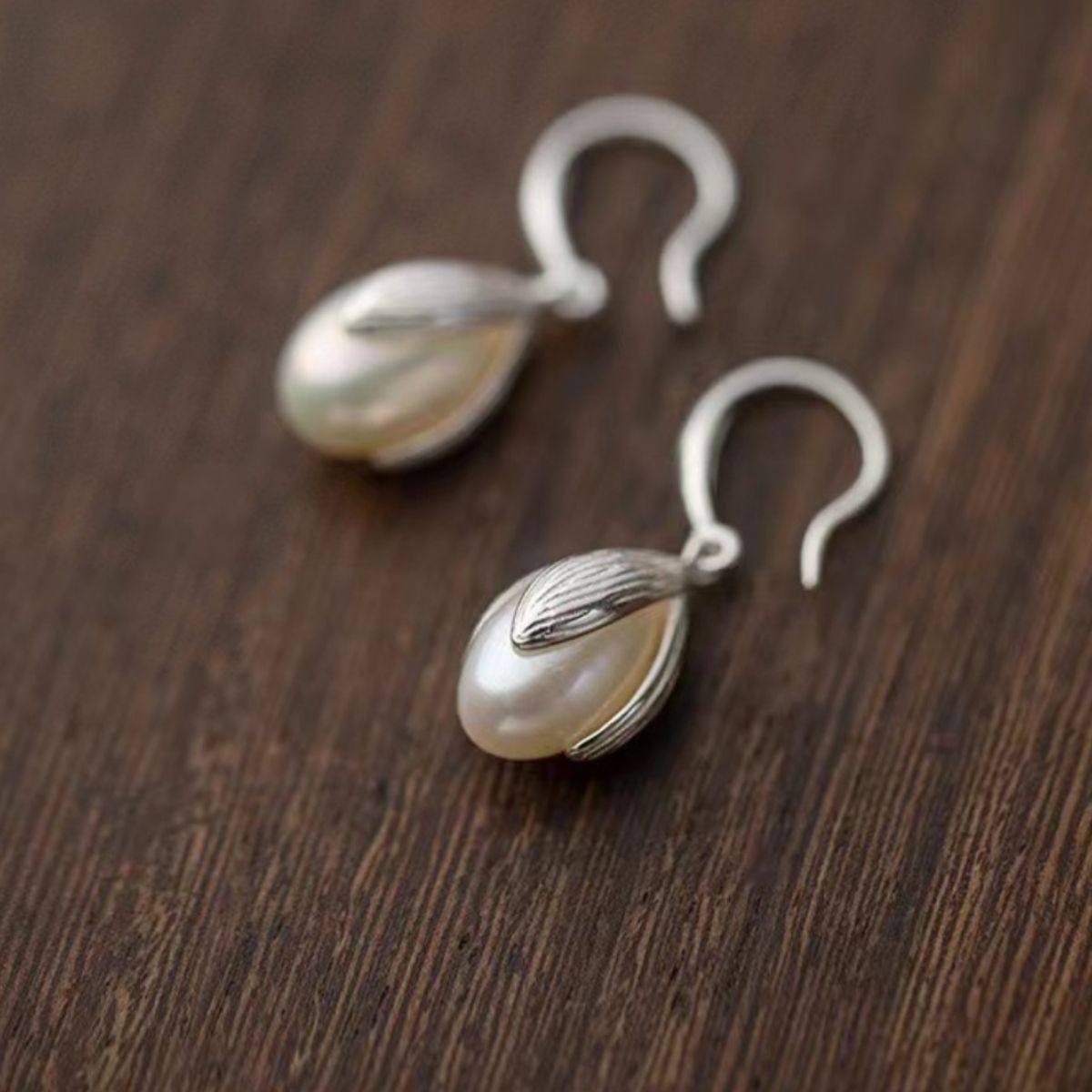 Lustrous pearl drop earrings with silver setting and hook clasps.