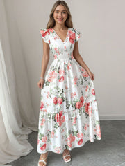 White floral maxi dress with ruffle sleeves, V-neck, smocked waist, and tiered skirt.